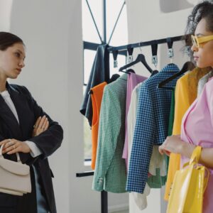 Two women browsing colorful clothing racks in a modern boutique.